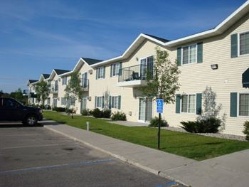 A row of townhomes with cars parked in front of them